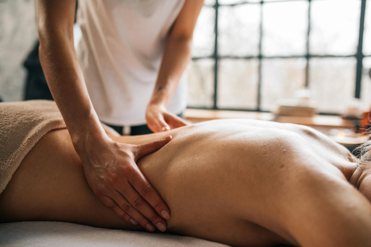 Therapeutic hands performing relaxing massage strokes synchronized with breathwork at Allure SPA Porto
